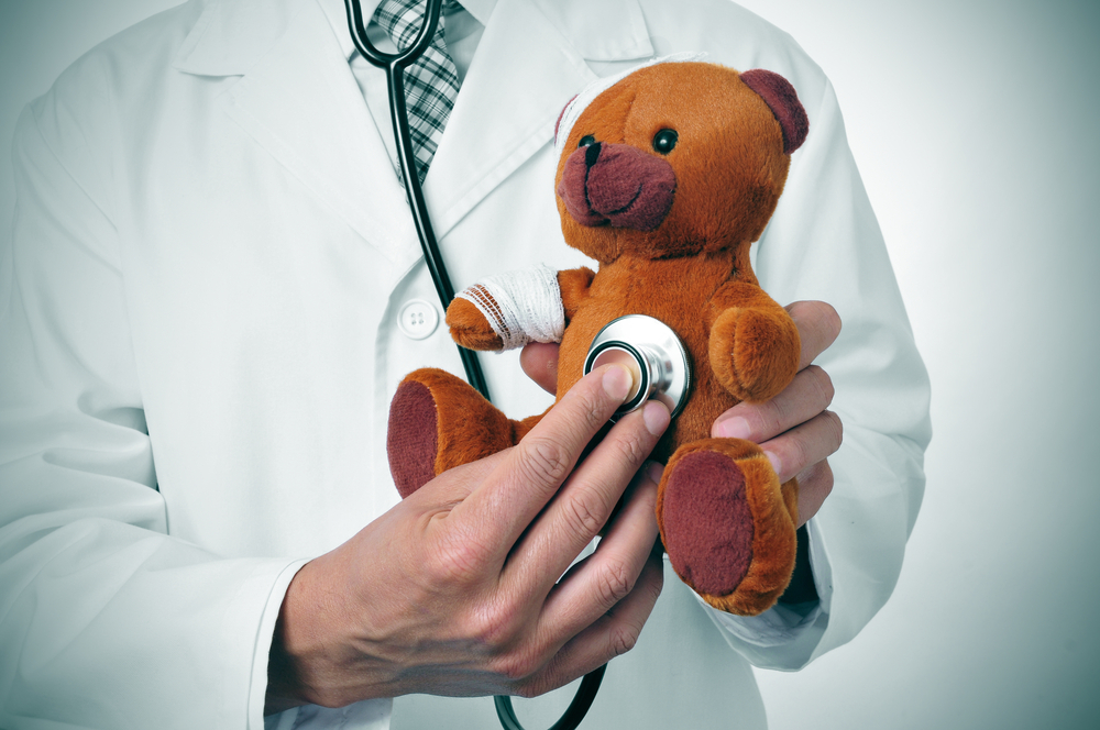 Un pédiatre faisant l'ausculte sur le coeur d'un ours en peluche représentant la médecine pédiatrique