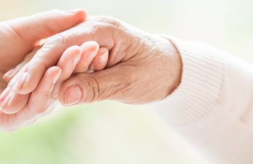 Gros plan sur un geste tendre entre deux générations. Jeune femme tenant la main d'une femme âgée.